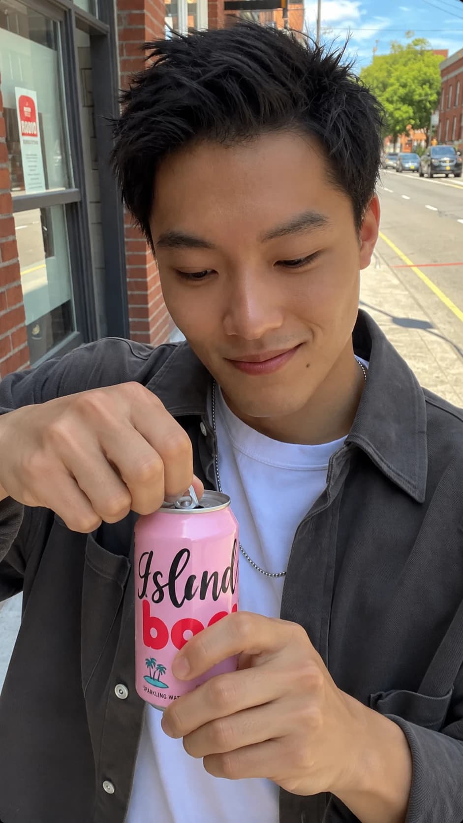 Creator cracking open the pink can on a sunny city sidewalk